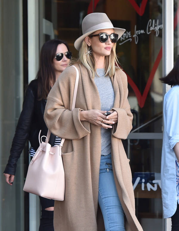 Rosie Huntington dạo phố với trang phục áo khoác dáng dài, mũ vành fedora và chiếc túi xô mini màu pastel rất ăn nhập với trang phục .